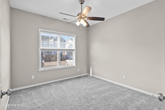 carpeted empty room with baseboards, visible vents, and a ceiling fan