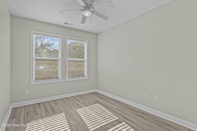 empty room with a ceiling fan, wood finished floors, visible vents, and baseboards