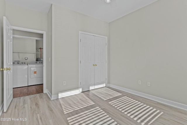 unfurnished bedroom with washing machine and dryer, a closet, wood finished floors, and baseboards