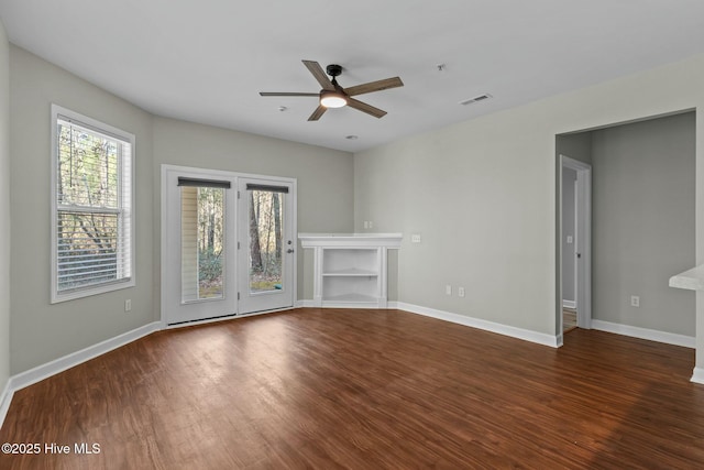 unfurnished living room featuring wood finished floors, visible vents, and baseboards