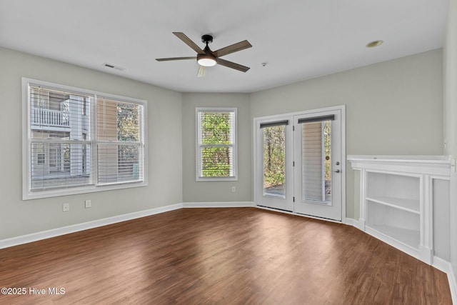 empty room with a ceiling fan, visible vents, baseboards, and wood finished floors