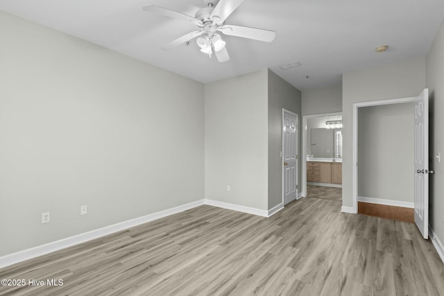 unfurnished bedroom with ensuite bathroom, light wood-style flooring, a ceiling fan, visible vents, and baseboards