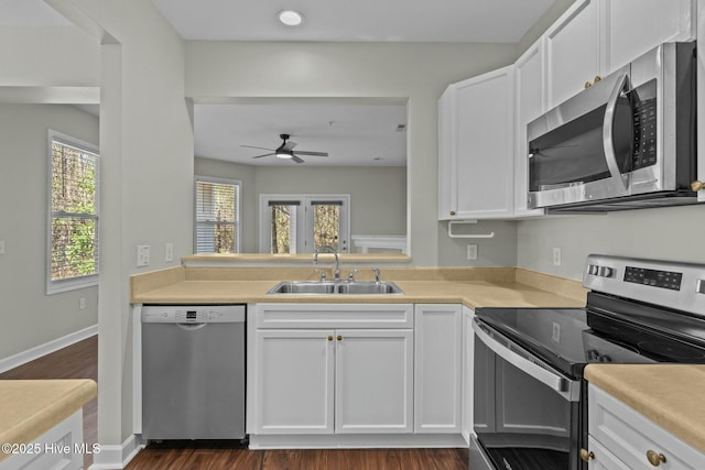 kitchen featuring stainless steel appliances, light countertops, a sink, and white cabinetry