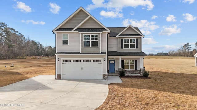 craftsman-style home featuring covered porch, a garage, stone siding, driveway, and a front lawn