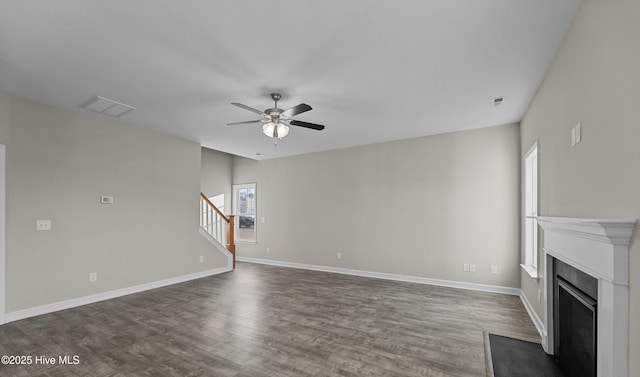 unfurnished living room with dark wood-style floors, visible vents, a fireplace, and stairs