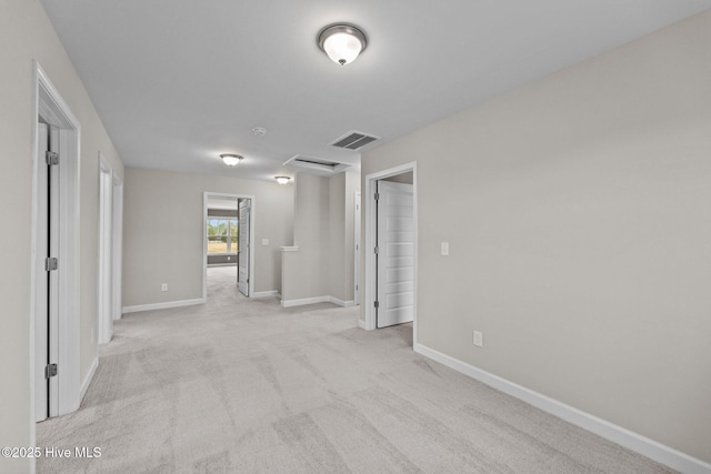 spare room featuring light carpet, visible vents, and baseboards