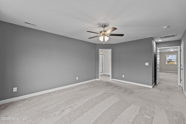 spare room featuring light colored carpet, visible vents, and baseboards