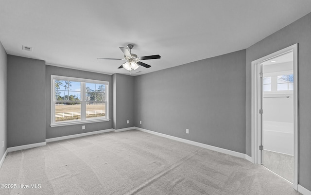 empty room with baseboards, visible vents, a ceiling fan, and light colored carpet