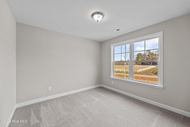 carpeted spare room featuring visible vents and baseboards