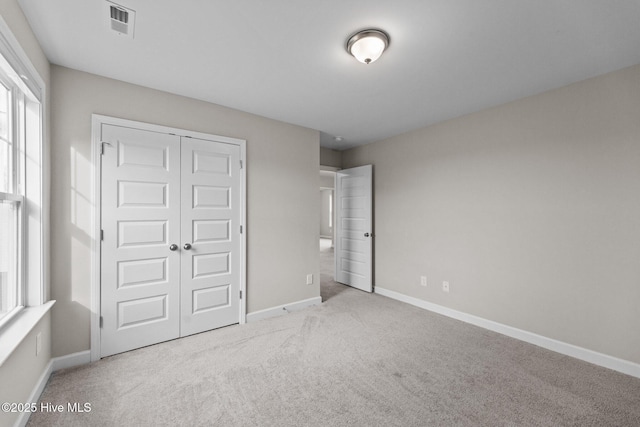 unfurnished bedroom with carpet, visible vents, baseboards, and a closet