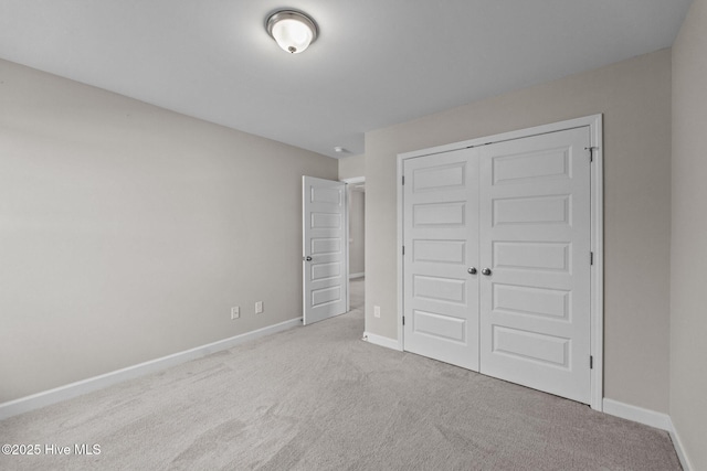 unfurnished bedroom featuring carpet, baseboards, and a closet