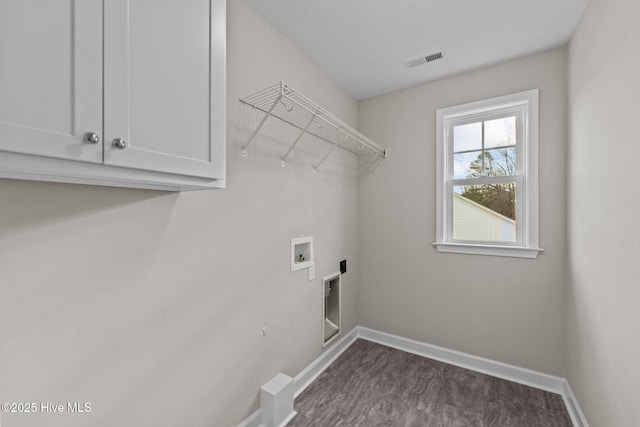 clothes washing area with washer hookup, cabinet space, visible vents, and baseboards