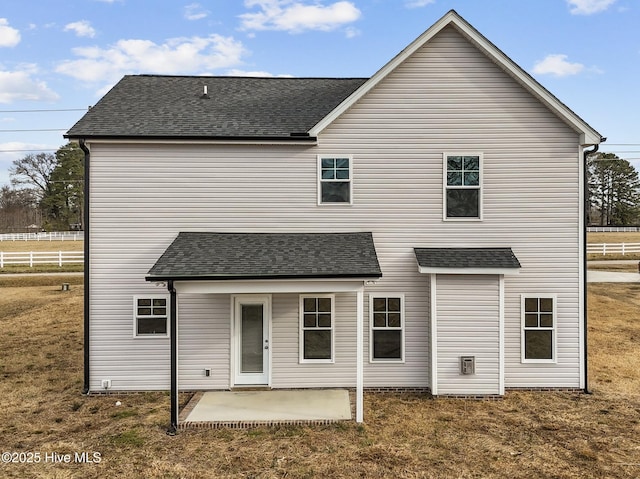 back of house featuring roof with shingles, fence, a lawn, and a patio