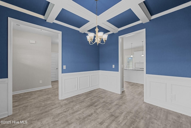 unfurnished dining area featuring coffered ceiling, a notable chandelier, beamed ceiling, and wood finished floors