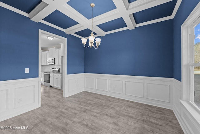 unfurnished dining area featuring beamed ceiling, light wood-type flooring, coffered ceiling, and a notable chandelier