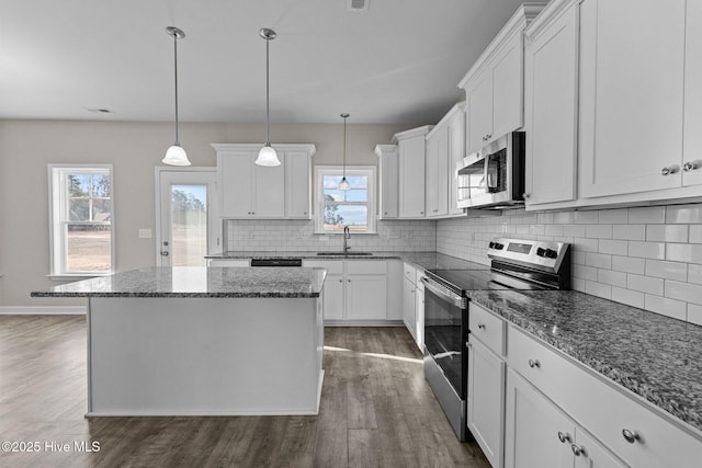 kitchen featuring stainless steel appliances, a kitchen island, a sink, white cabinetry, and dark wood finished floors