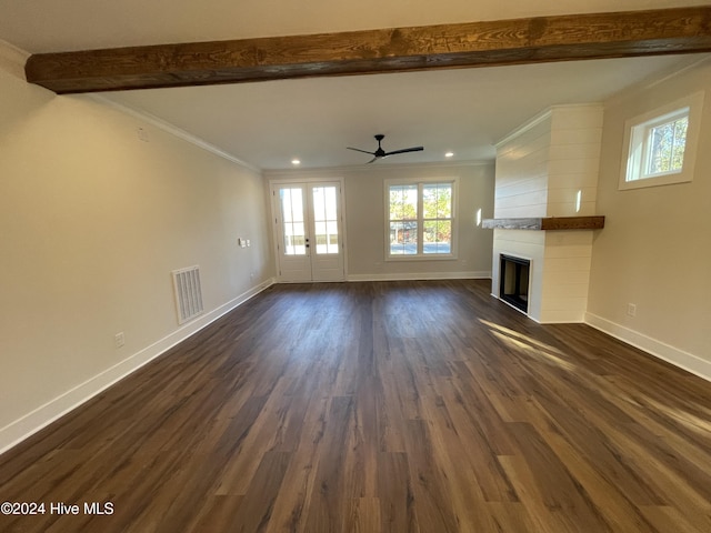 unfurnished living room featuring dark wood-style floors, beam ceiling, a fireplace, crown molding, and baseboards