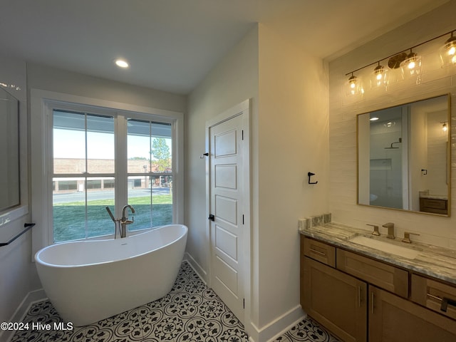 bathroom featuring recessed lighting, vanity, tile patterned flooring, a freestanding tub, and baseboards