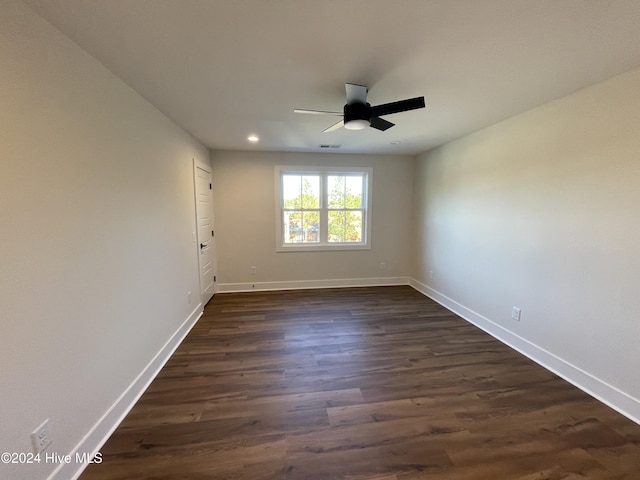 spare room with dark wood-style floors, visible vents, a ceiling fan, and baseboards