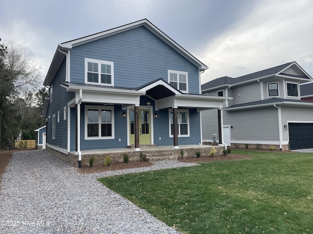 view of front facade with a front yard, covered porch, and gravel driveway