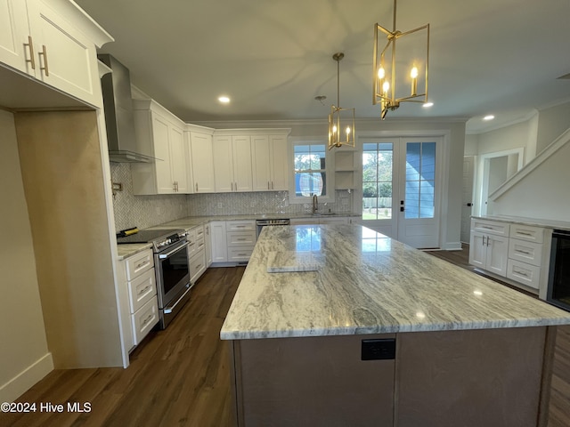 kitchen with stainless steel appliances, backsplash, ornamental molding, a kitchen island, and wall chimney range hood