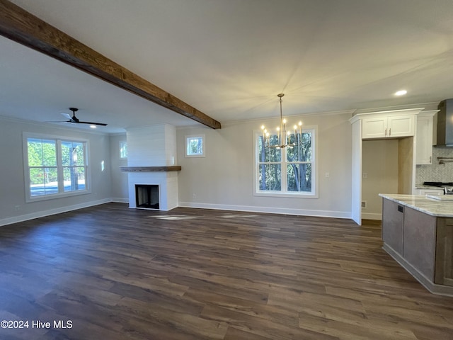 unfurnished living room featuring a wealth of natural light, beam ceiling, a fireplace, and dark wood-style flooring