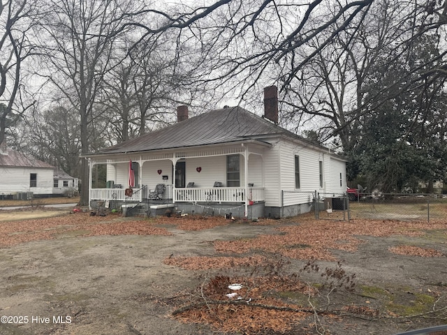 view of front of home featuring a porch, fence, and a chimney