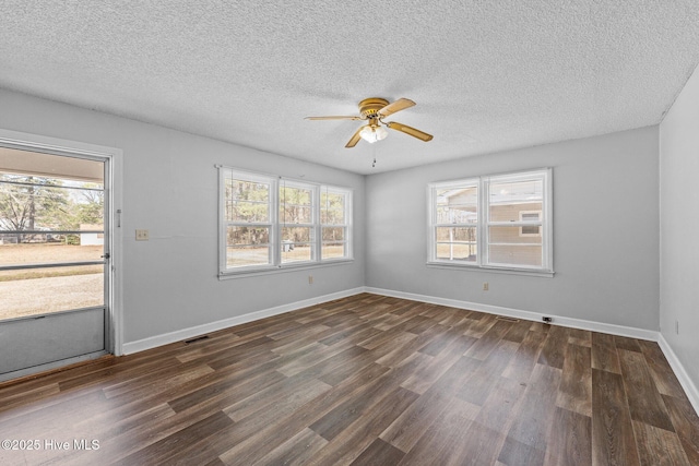 unfurnished room featuring dark wood-style floors, visible vents, a textured ceiling, and baseboards