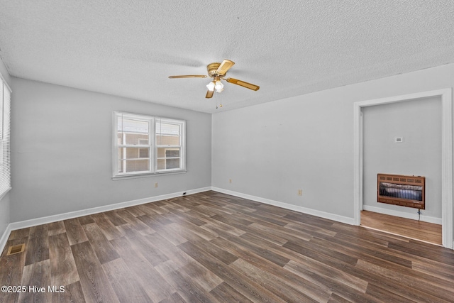 unfurnished room with dark wood-style flooring, heating unit, visible vents, ceiling fan, and baseboards