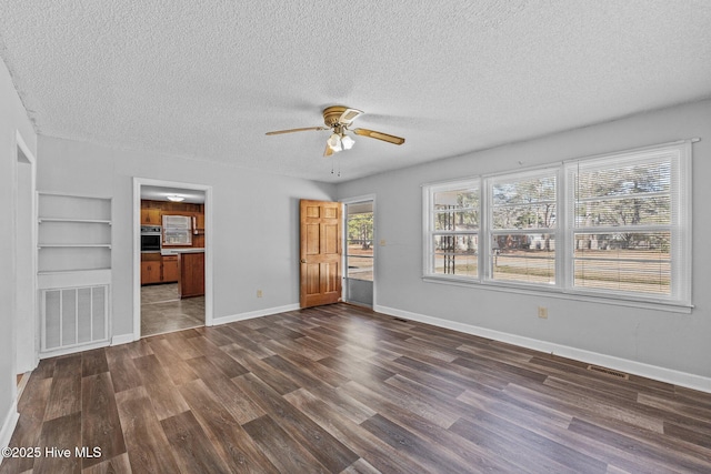 interior space with dark wood-style flooring, visible vents, a textured ceiling, and baseboards