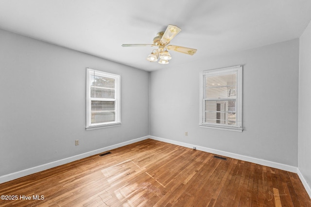 empty room with a healthy amount of sunlight, baseboards, and hardwood / wood-style floors