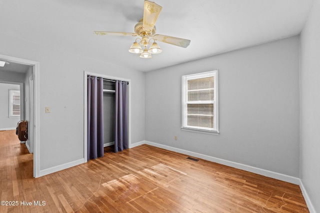 unfurnished bedroom featuring light wood finished floors, baseboards, visible vents, and a closet