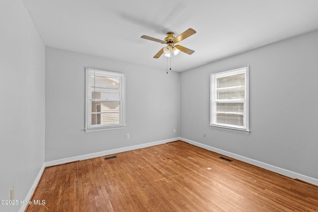 spare room featuring light wood finished floors, visible vents, and a wealth of natural light