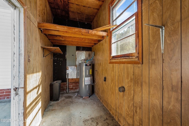 interior space with wood walls, electric water heater, and electric panel