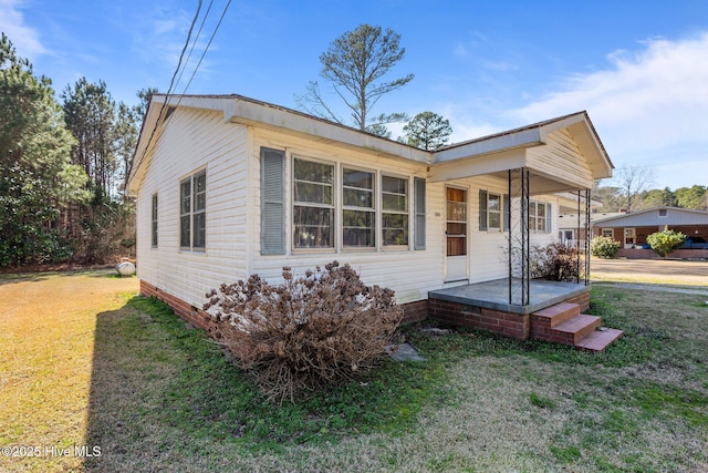 bungalow-style house featuring covered porch and a front yard