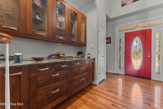 foyer entrance with baseboards, light wood-style floors, and crown molding