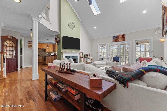 living room with a skylight, crown molding, recessed lighting, light wood-style flooring, and a premium fireplace