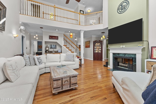 living room featuring ornamental molding, wood finished floors, stairs, ornate columns, and a fireplace