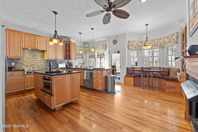 kitchen with appliances with stainless steel finishes, dark countertops, a center island, and light wood-type flooring