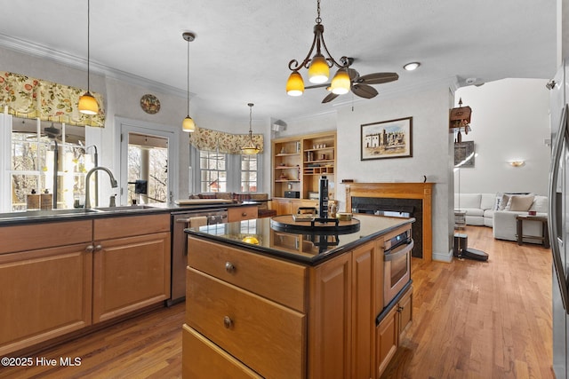 kitchen featuring dark countertops, appliances with stainless steel finishes, ornamental molding, wood finished floors, and a fireplace