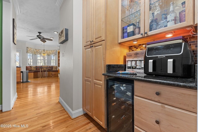 kitchen with light wood finished floors, beverage cooler, baseboards, a ceiling fan, and glass insert cabinets