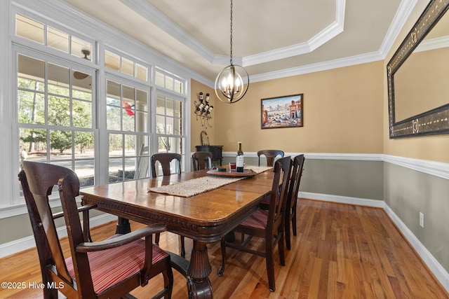 dining space featuring a notable chandelier, crown molding, baseboards, and wood finished floors