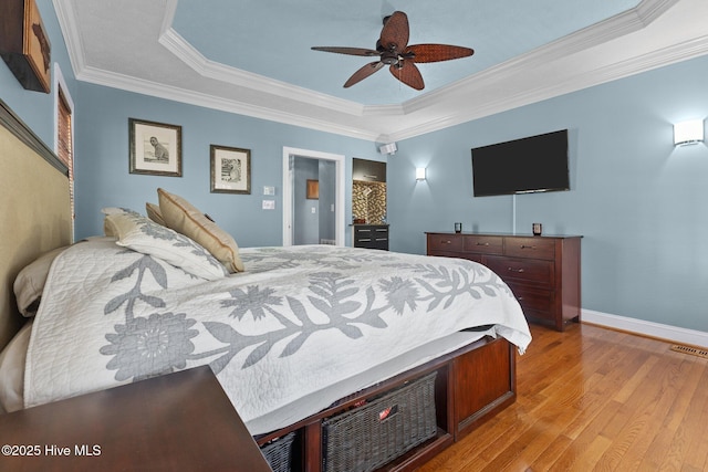 bedroom featuring visible vents, baseboards, ornamental molding, light wood finished floors, and a raised ceiling