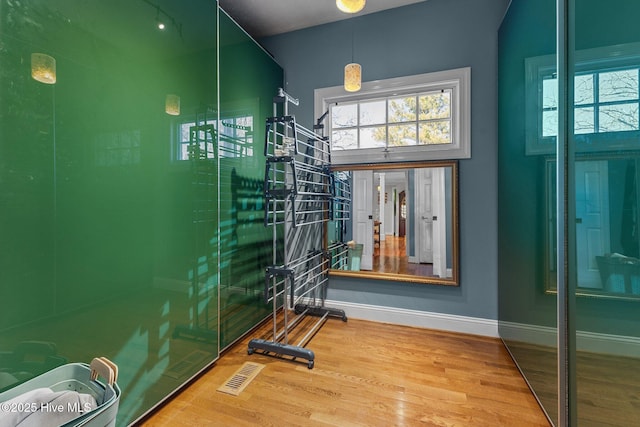 workout room featuring visible vents, baseboards, and wood finished floors