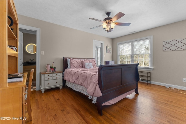 bedroom with visible vents, a ceiling fan, a textured ceiling, wood finished floors, and baseboards