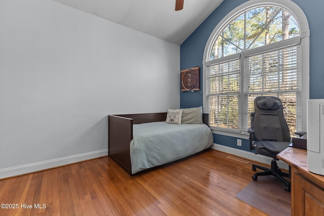 bedroom featuring hardwood / wood-style flooring, baseboards, and vaulted ceiling