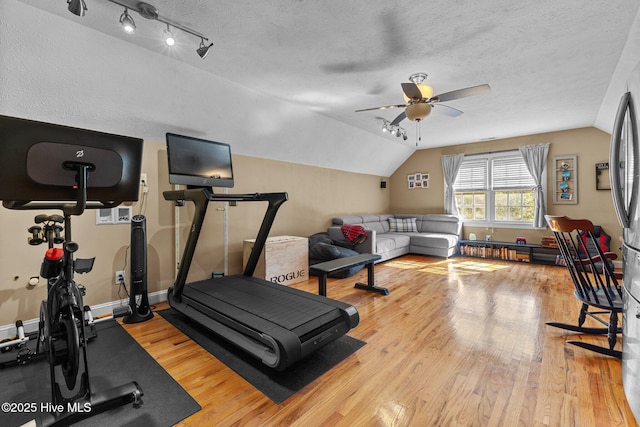 exercise room with vaulted ceiling, a textured ceiling, and wood finished floors