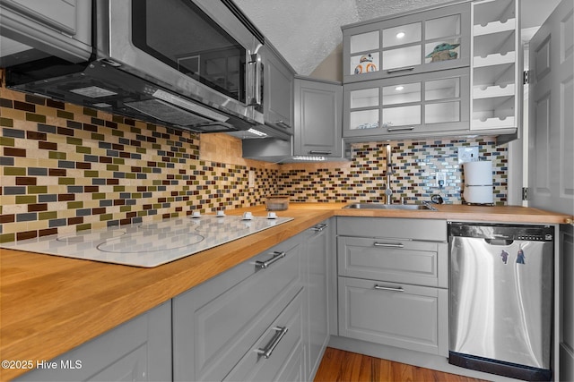 kitchen featuring appliances with stainless steel finishes, butcher block counters, gray cabinets, and backsplash