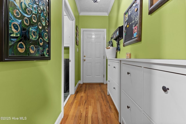 interior space featuring a textured ceiling, ornamental molding, and light wood-style floors