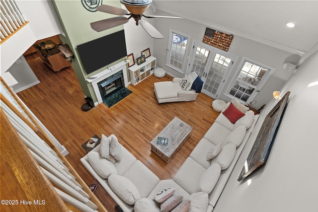 living area with crown molding, recessed lighting, a fireplace with flush hearth, ceiling fan, and wood finished floors